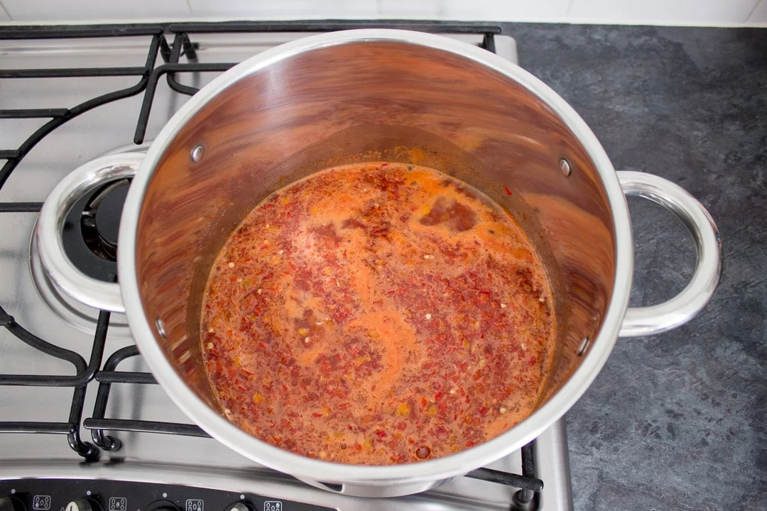 sweet chilli jam ingredients in a large pot on the hob with scum on the top