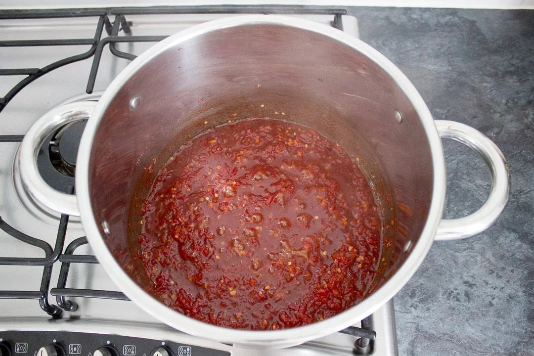 reducing sweet chilli jam in a large pot on the hob