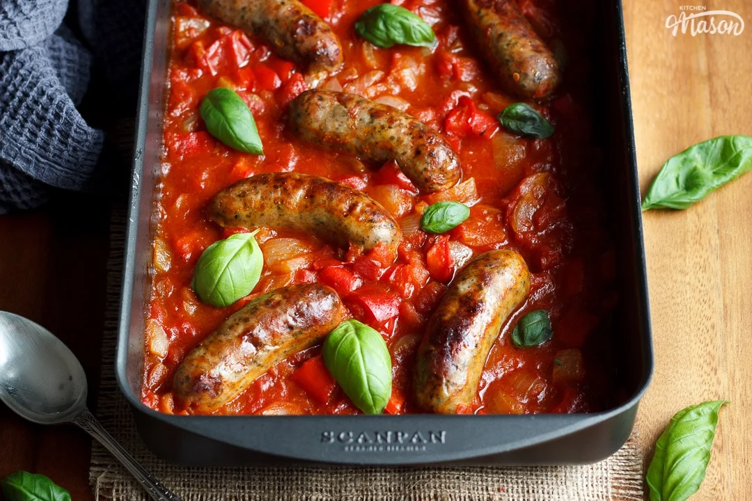 easy sausage casserole in a roasting dish topped with fresh basil leaves