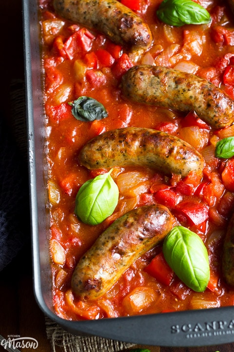 easy sausage casserole in a roasting dish topped with fresh basil leaves