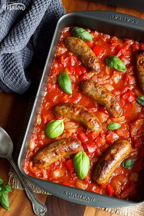 easy sausage casserole in a roasting dish topped with fresh basil leaves