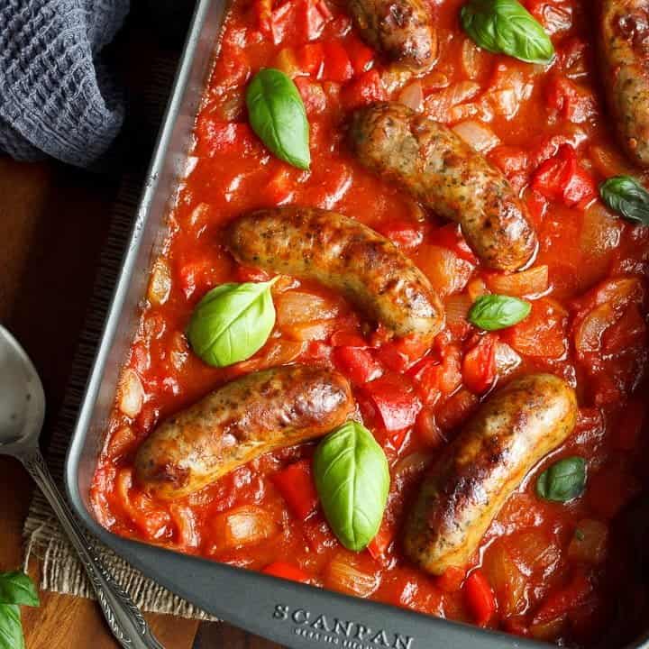 easy sausage casserole in a roasting dish topped with fresh basil leaves
