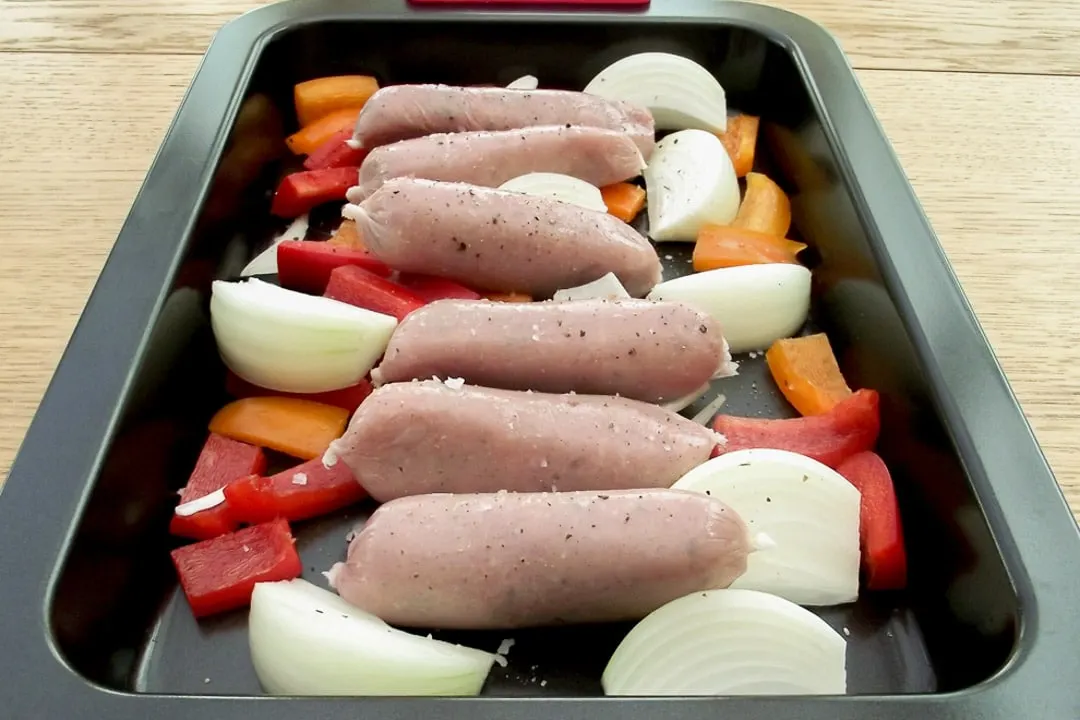 sausages, red pepper, orange pepper & onion in a baking tray