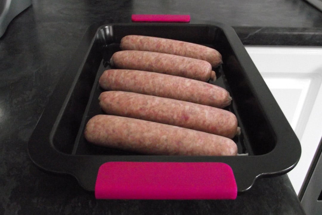 sausages lined up in a roasting tray