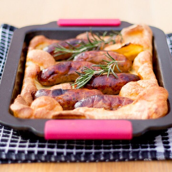 Toad in the hole in a roasting tray on a black and white tea towel
