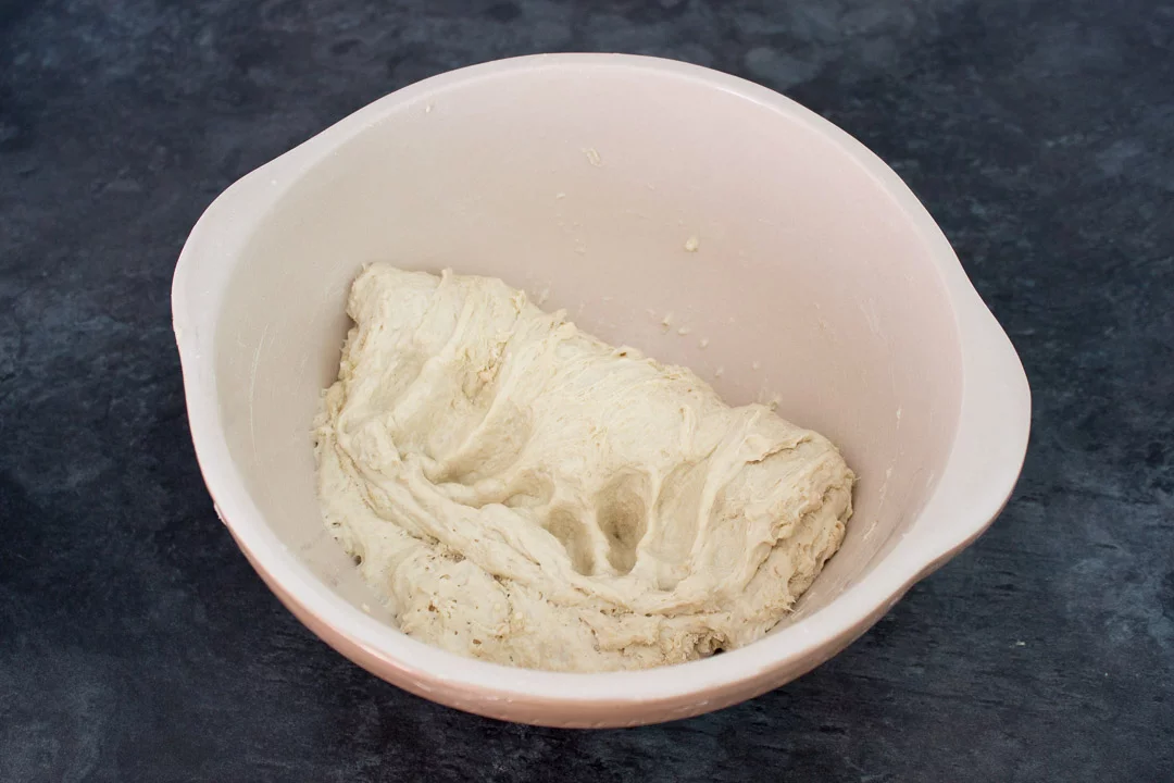 No knead bread dough in a large mixing bowl after being folded in on itself