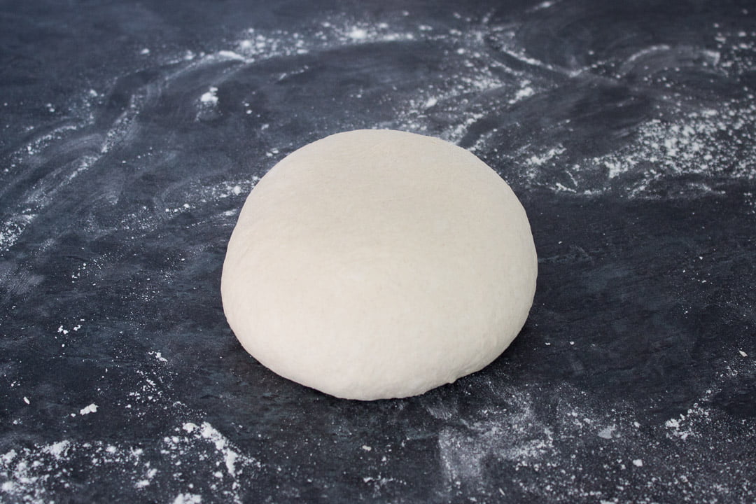 A ball of no knead bread dough on a floured work surface