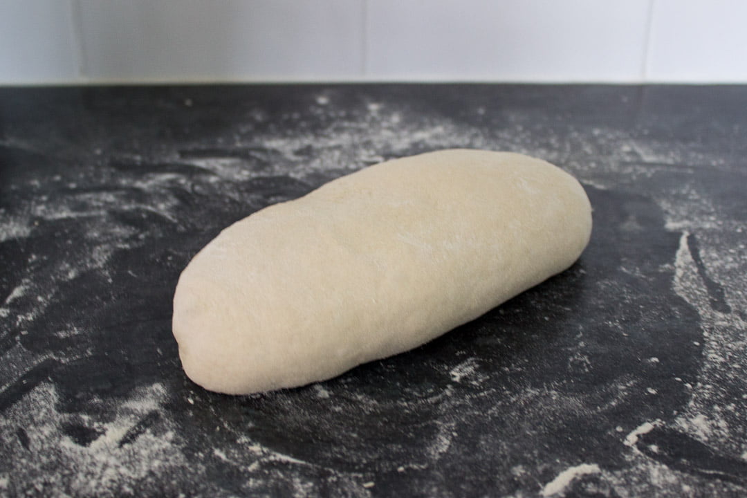 Loaf shaped no knead bread dough on a floured work surface