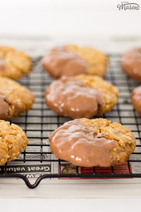 Chocolate hobnobs on a cooling rack set over newspaper dipped in chocolate