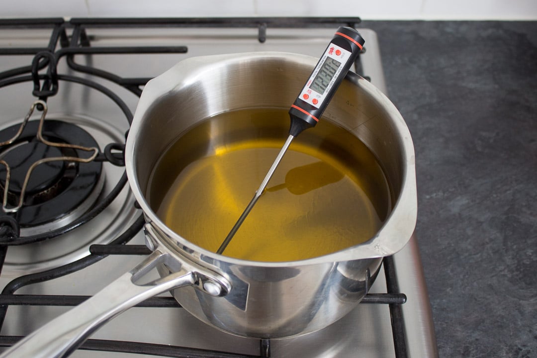 oil heating up in a large pan with a termometer