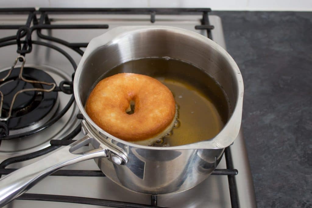 homemade doughnut being baked in a pan of hot oil