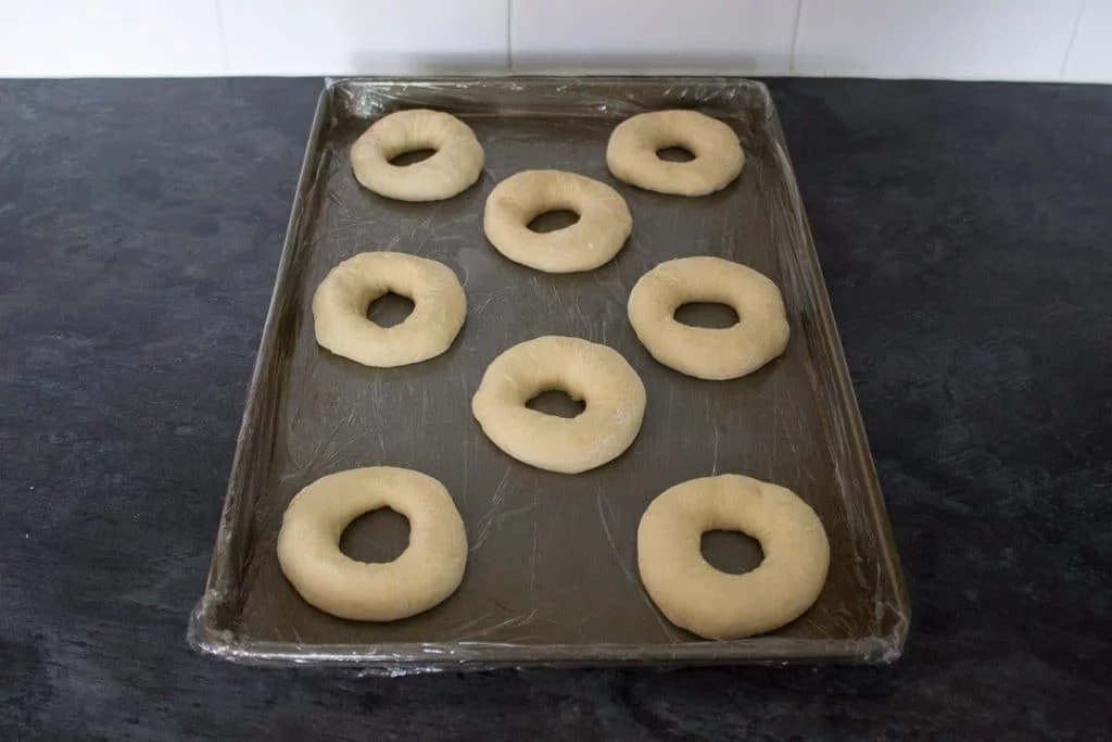 unbaked homemade doughnut rings on a baking tray