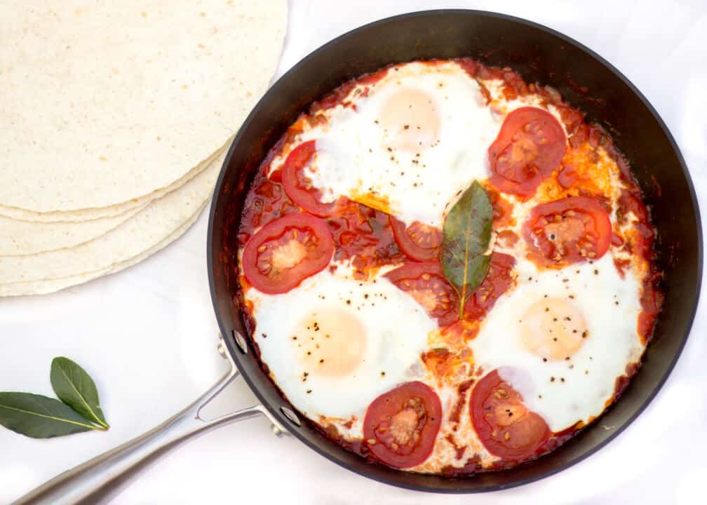 Mexican breakfast in a large pan with tortilla wraps at the side