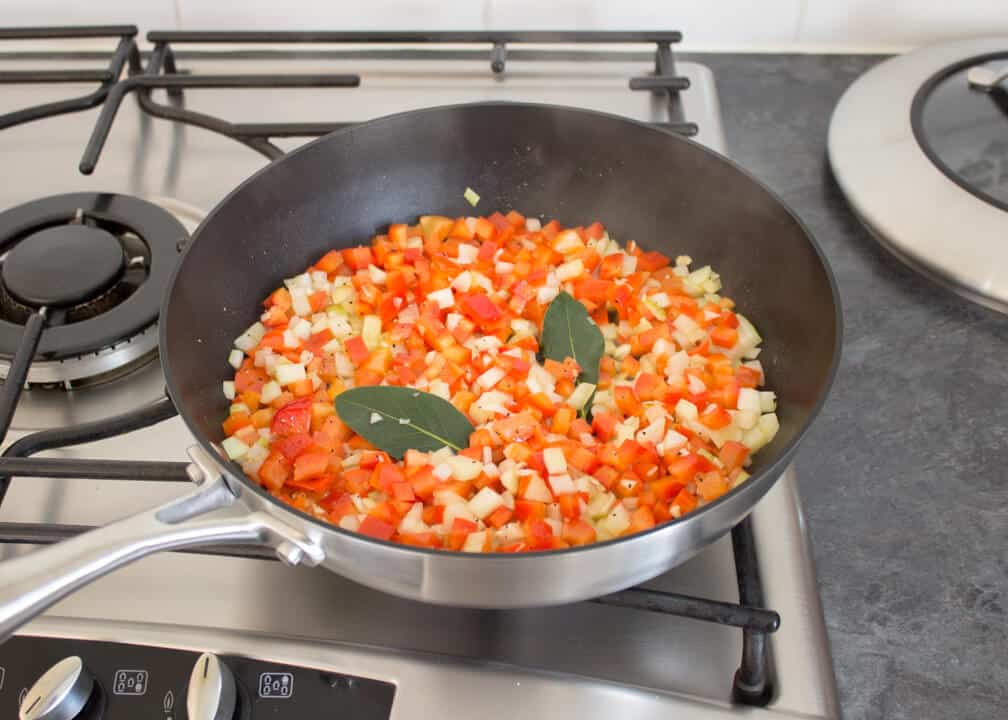Onion, garlic, red pepper, chilli and bay leaves frying in a pan