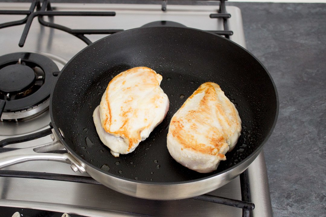 2 chicken breasts frying in a frying pan