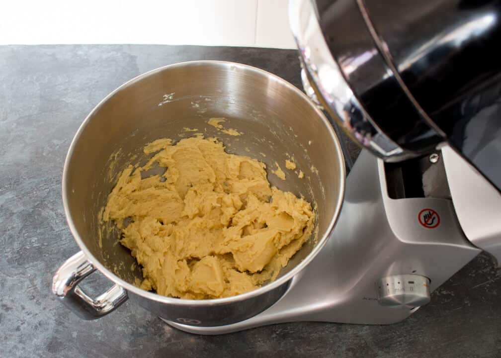 Butter, sugar, vanilla and egg creamed together in an electric stand mixer on a kitchen worktop.