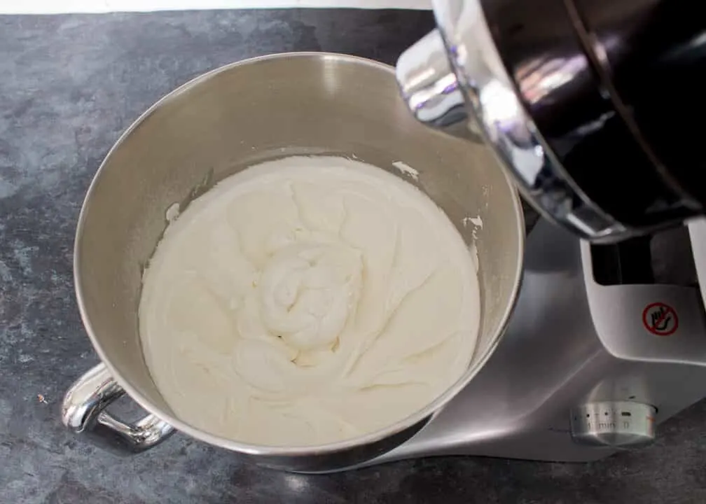 Egg whites, icing sugar and lemon juice that's been whisked to stiff peaks and thinned with water in an electric stand mixer on a kitchen worktop.