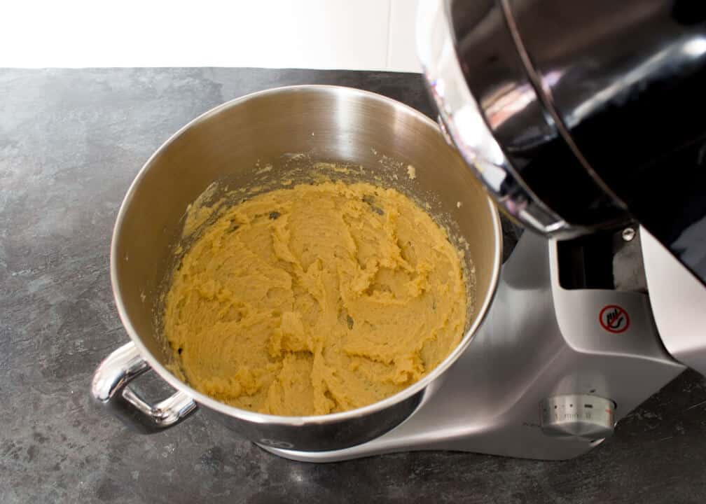 Butter, sugar and vanilla creamed together in an electric stand mixer on a kitchen worktop.