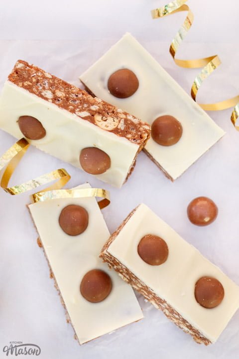 Malteser Tiffin Bars and gold curling ribbon lay on a table.