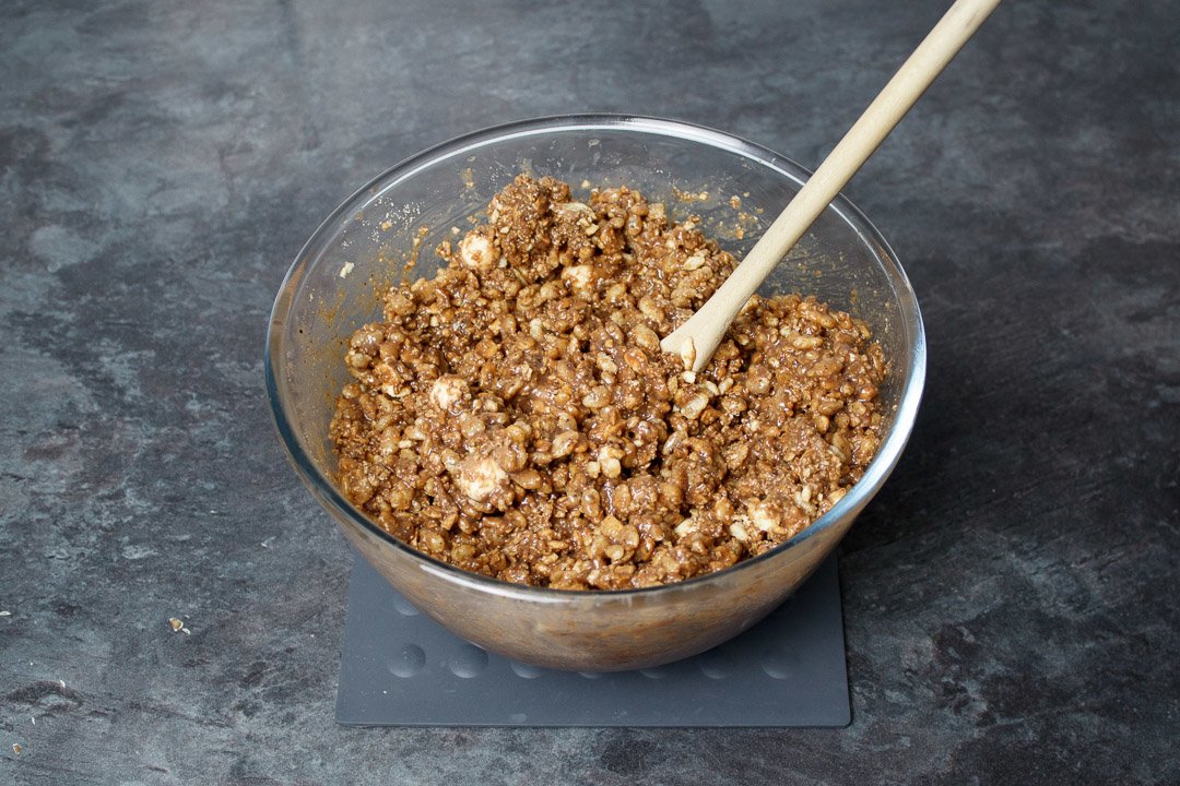 Malteser tiffin mixture in a glass bowl with a wooden spoon
