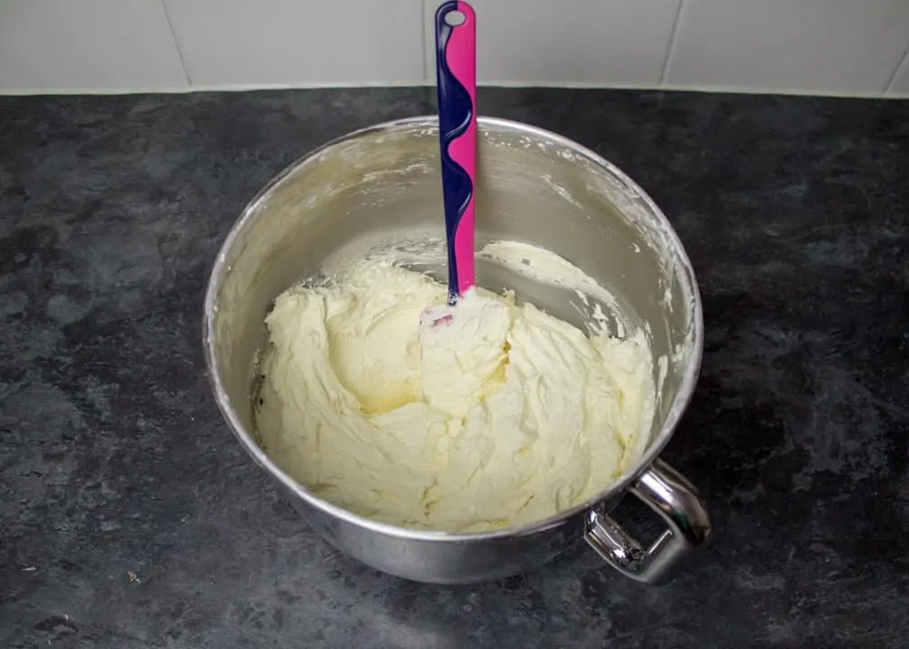 Vanilla frosting in a large mixing bowl with a spatula