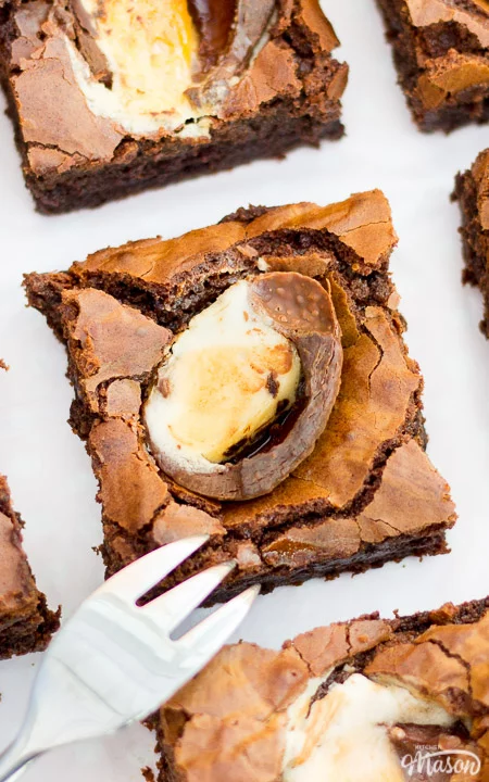 Creme egg brownies cut into squares on a sheet of baking paper with a fork