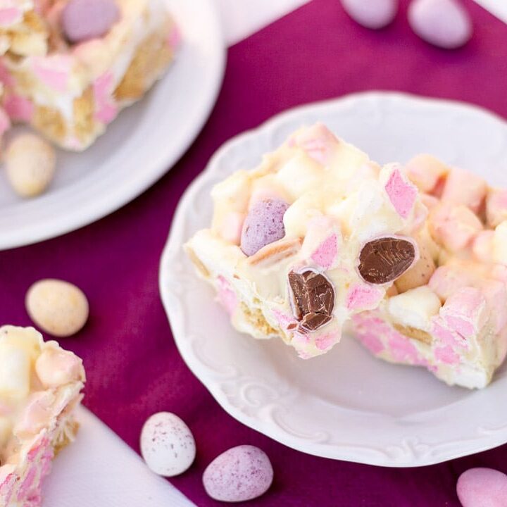 Mini Egg rocky road bars on a white plate with Mini Eggs scattered around.