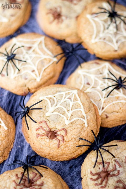 chocolate chip halloween spider cookies on a spider web with black plastic spiders