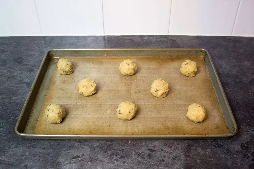 spider cookie dough balls on a lined baking sheet