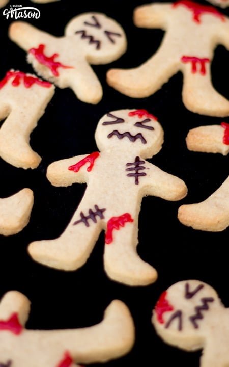 Close up flat lay view of a few decorated ginger-dead men Halloween biscuits against a black background.