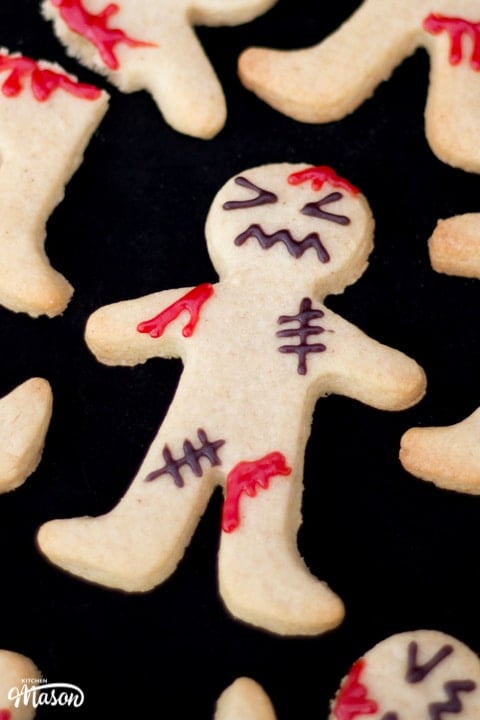 Close up flat lay view of a decorated ginger-dead man Halloween biscuits against a black background.