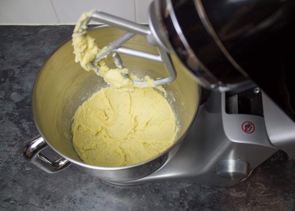 Creamed butter and sugar in an electric stand mixer on a kitchen worktop.