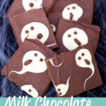 Milk chocolate ghost halloween bark cut into bars and laid on a cobweb covered black piece of fabric.