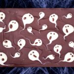 A whole slab of milk chocolate ghost halloween bark laid on a cobweb covered black piece of fabric.
