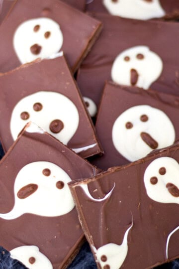 Milk chocolate ghost halloween bark cut into bars and laid on a cobweb covered black piece of fabric.