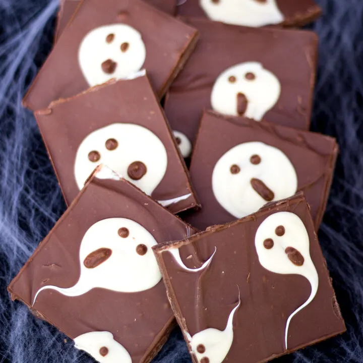 Milk chocolate ghost halloween bark cut into bars and laid on a cobweb covered black piece of fabric.