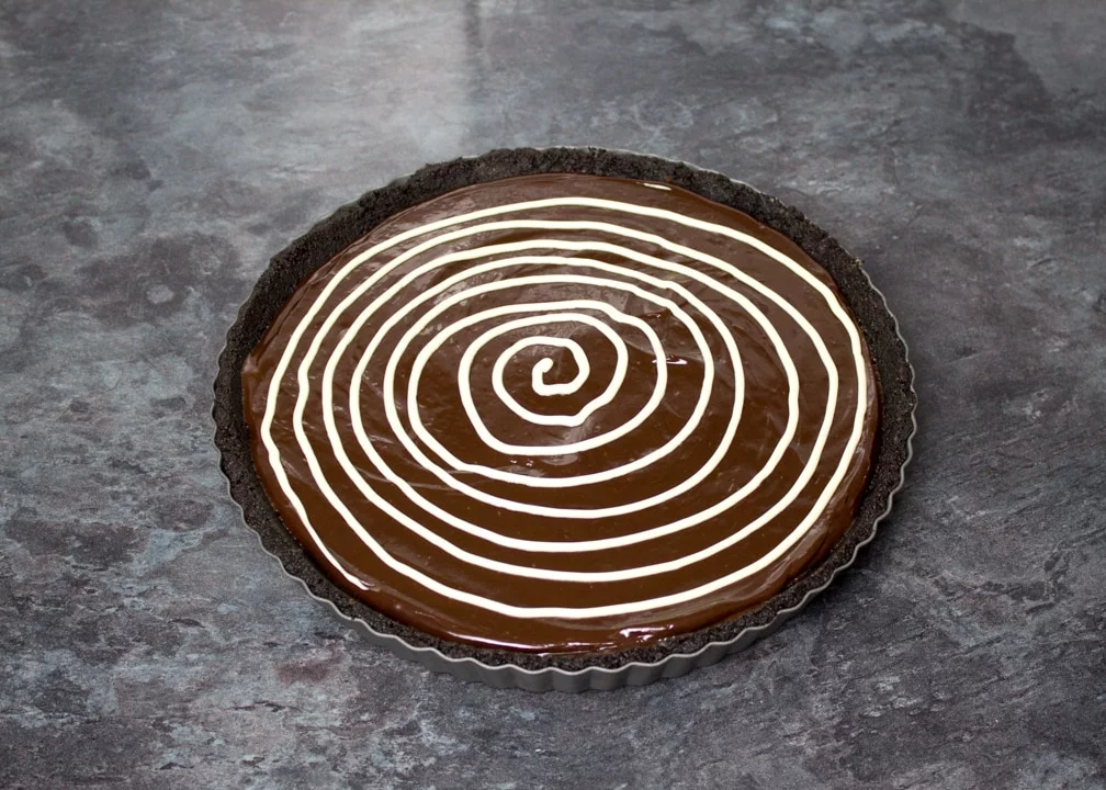White chocolate spiral piped over a chocolate tart