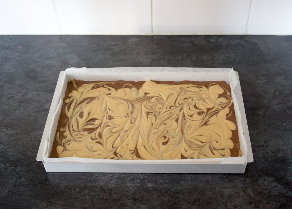 Peanut Butter Cookie Bark: melted milk chocolate in a baking tin with peanut butter chocolate swirled on top