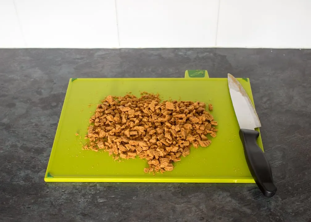Chopped Biscoff biscuits on a green chopping board