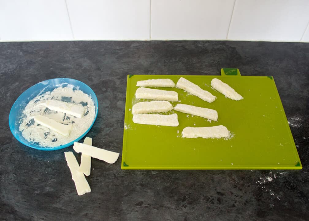 Uncooked Halloumi fries on a chopping board