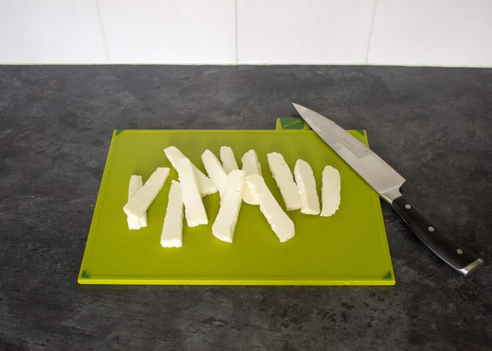Uncooked Halloumi fries on a chopping board