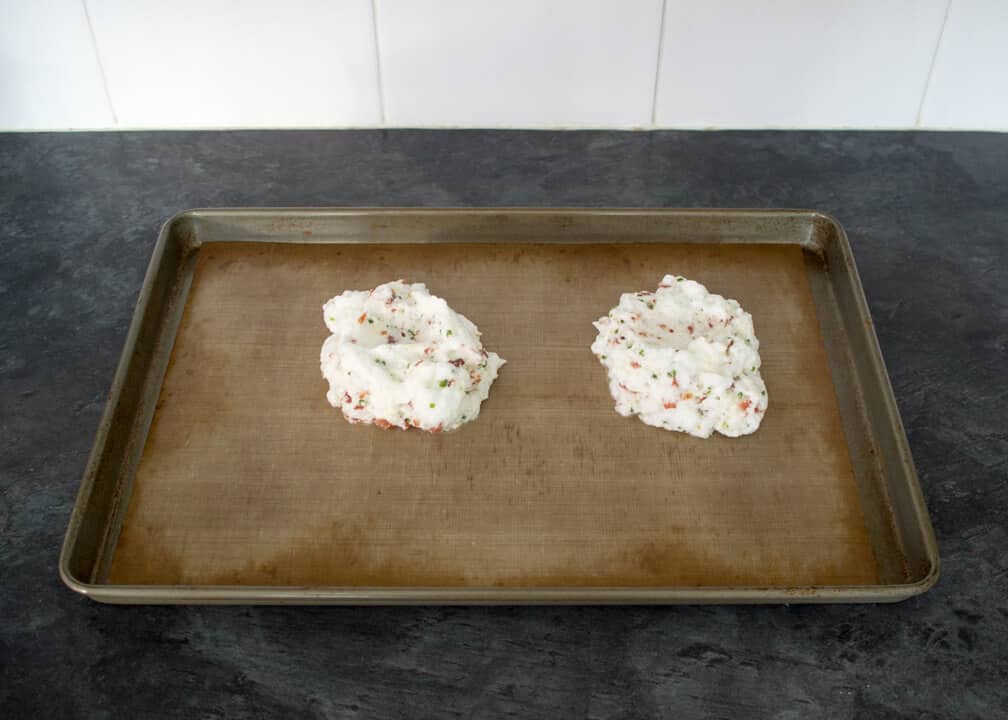 Bacon chive parmesan egg whites spooned into mounds on a baking tray