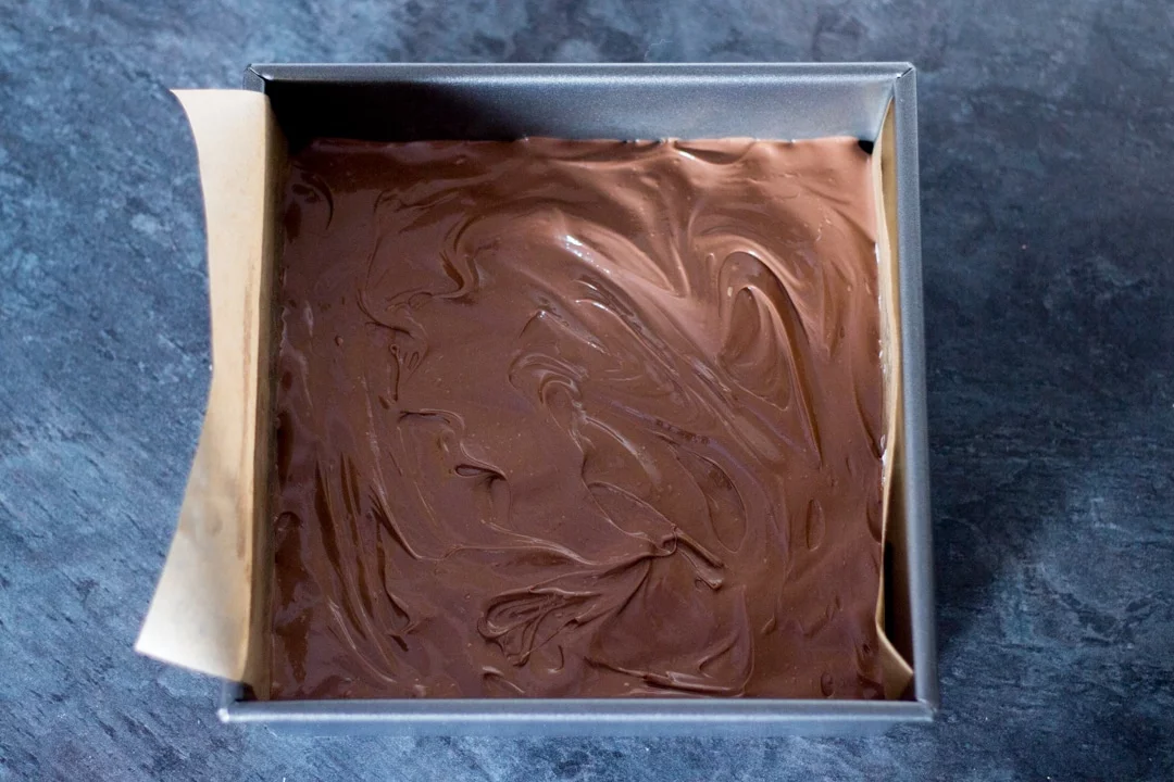 melted chocolate smoothed over a rice krispie marshmallow mixture in a baking tin