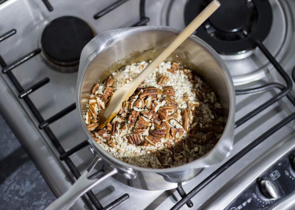 Flapjack Recipe: oats and pecans added into melted butter sugar and golden syrup in a saucepan