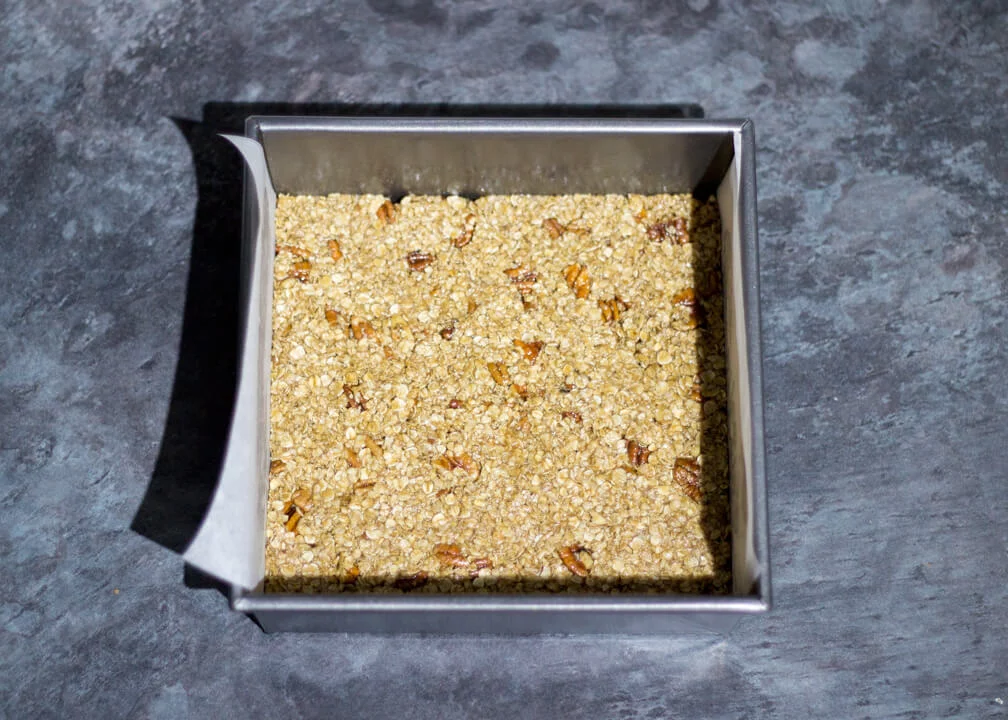 Flapjack Recipe: maple pecan flapjack mixture pressed into a lined square baking tin