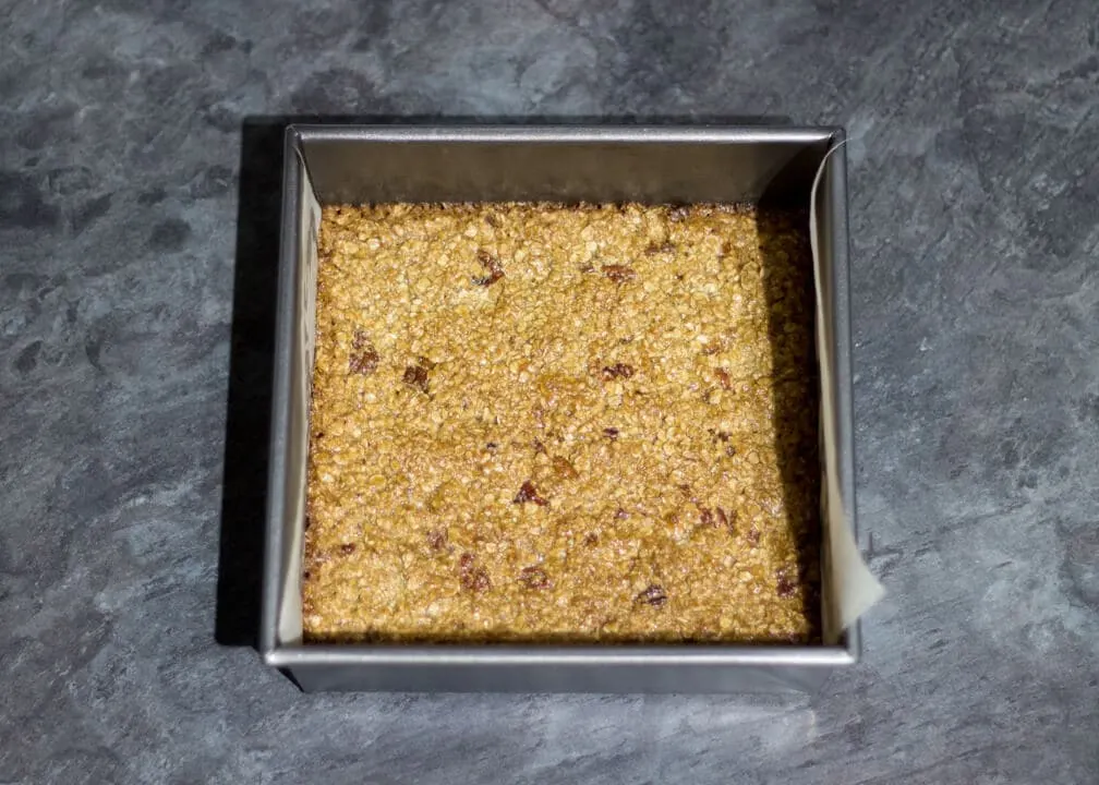 Flapjack Recipe: baked maple pecan flapjack in a lined square baking tin