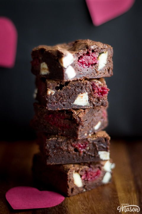 White chocolate raspberry brownies in a stack on a wooden worktop