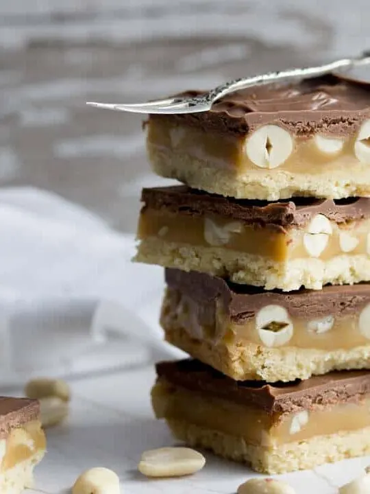 Snickers Millionaire Shortbread in a stack with a fork