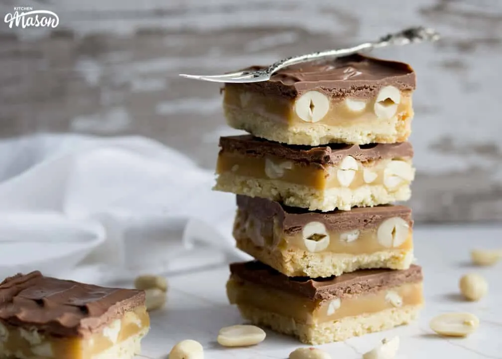 Snickers Millionaire Shortbread in a stack with a fork