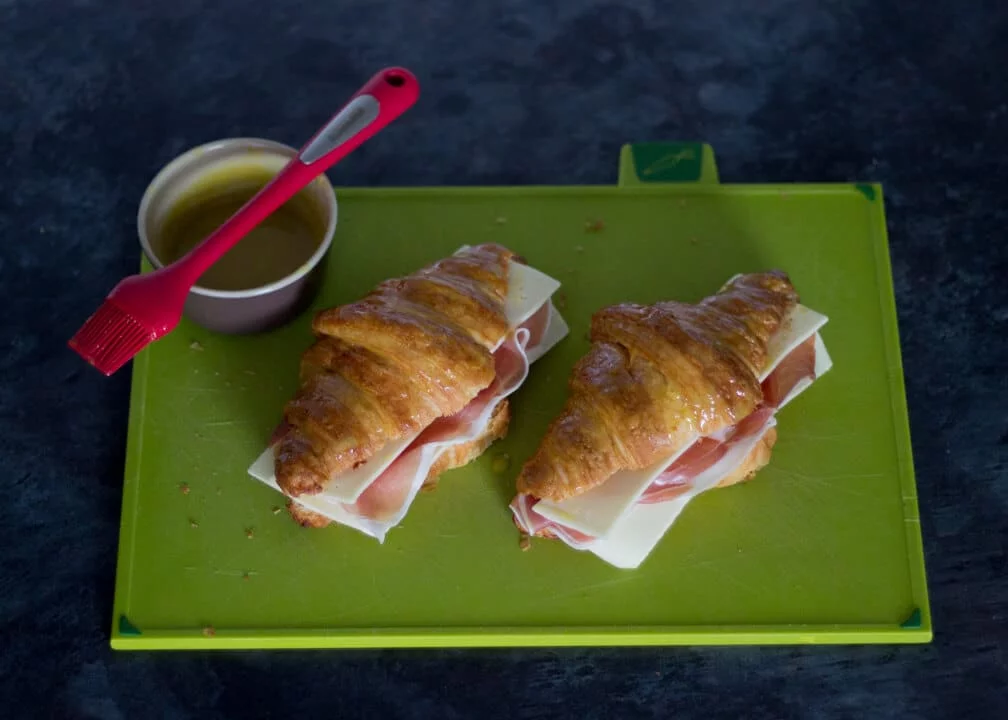 Croissant Sandwich with Prosciutto & Gouda on a Chopping Board with Mustard Glaze